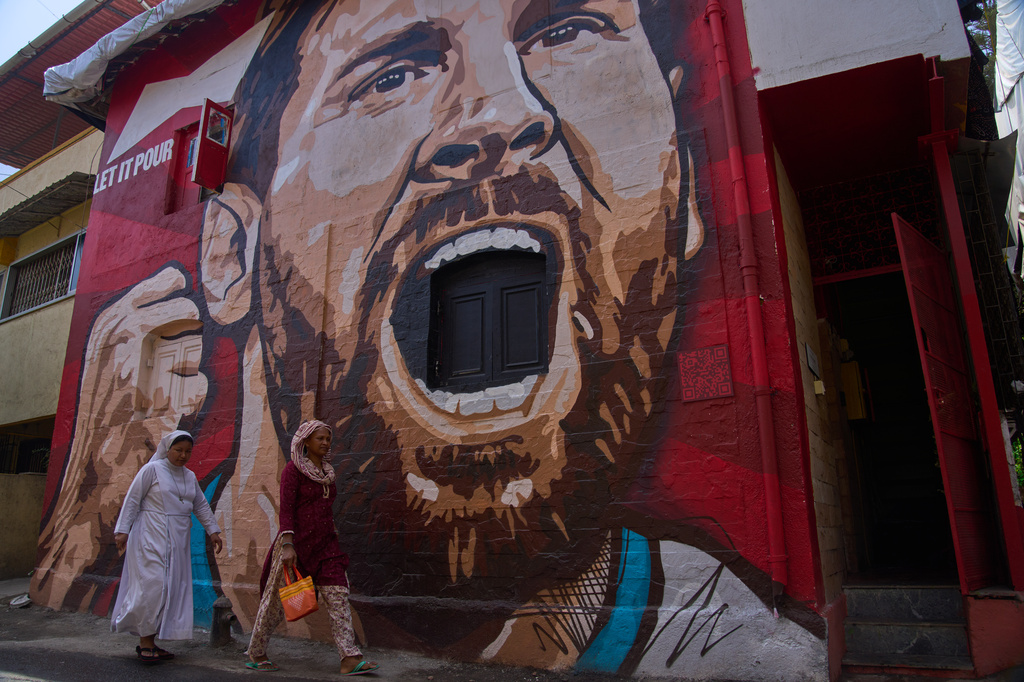 Women walk past a mural of Argentinian soccer player Lionel Messi made by Mooz Graffiti in Mumbai, India, Monday, June 15, 2026. (AP Photo/Rafiq Maqbool)