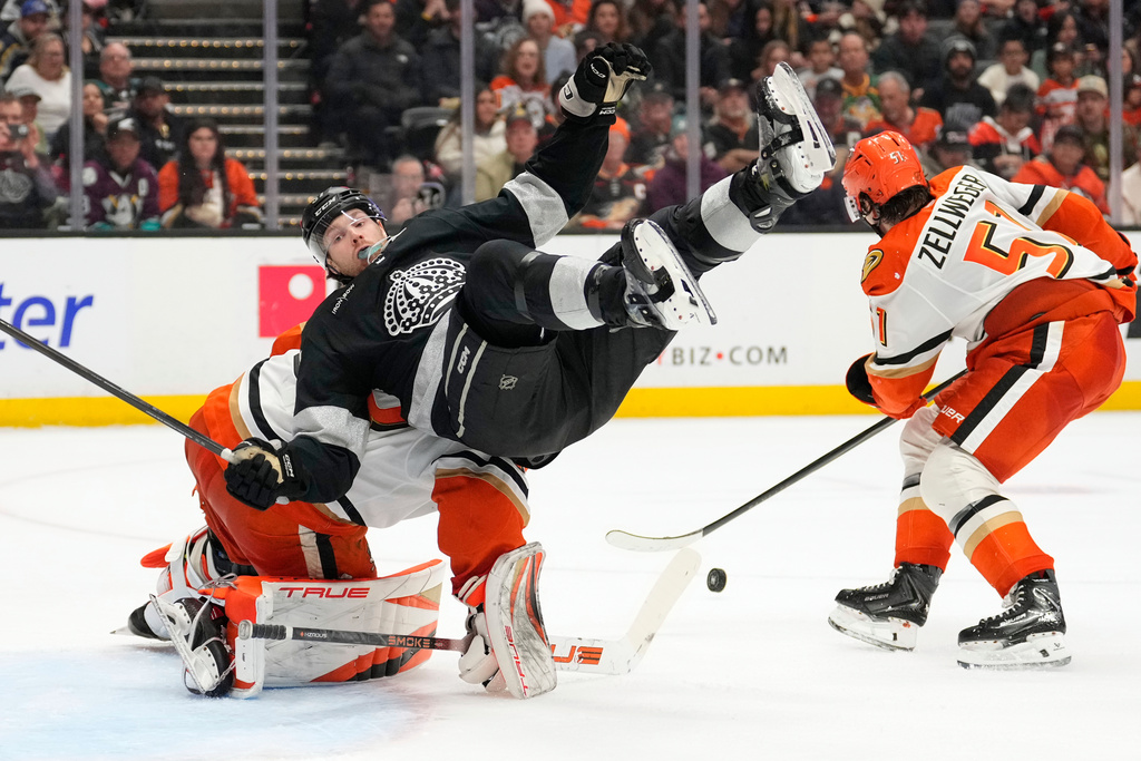 Los Angeles Kings left wing Warren Foegele, center, falls over Anaheim Ducks goaltender Ville Husso, left, as defenseman Olen Zellweger takes the puck during the second period of an NHL hockey game Saturday, Jan. 17, 2026, in Anaheim, Calif. (AP Photo/Mark J. Terrill)