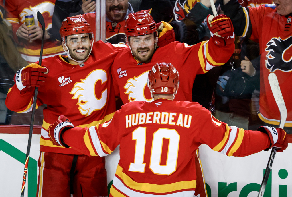 Calgary Flames' Matt Coronato, left, celebrates his goal with teammates Rasmus Andersson, center, and Jonathan Huberdeau during the third period of an NHL hockey game against the Seattle Kraken in Calgary, Alberta, Thursday, Dec. 18, 2025. (Jeff McIntosh/The Canadian Press via AP)