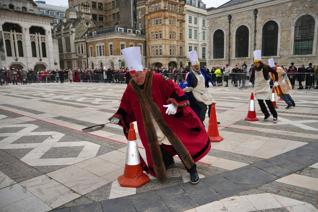 Competitors participate in a traditional pancake race by livery companies at the Guildhall in London, Tuesday, Feb. 17, 2026. (AP Photo/Kin Cheung)