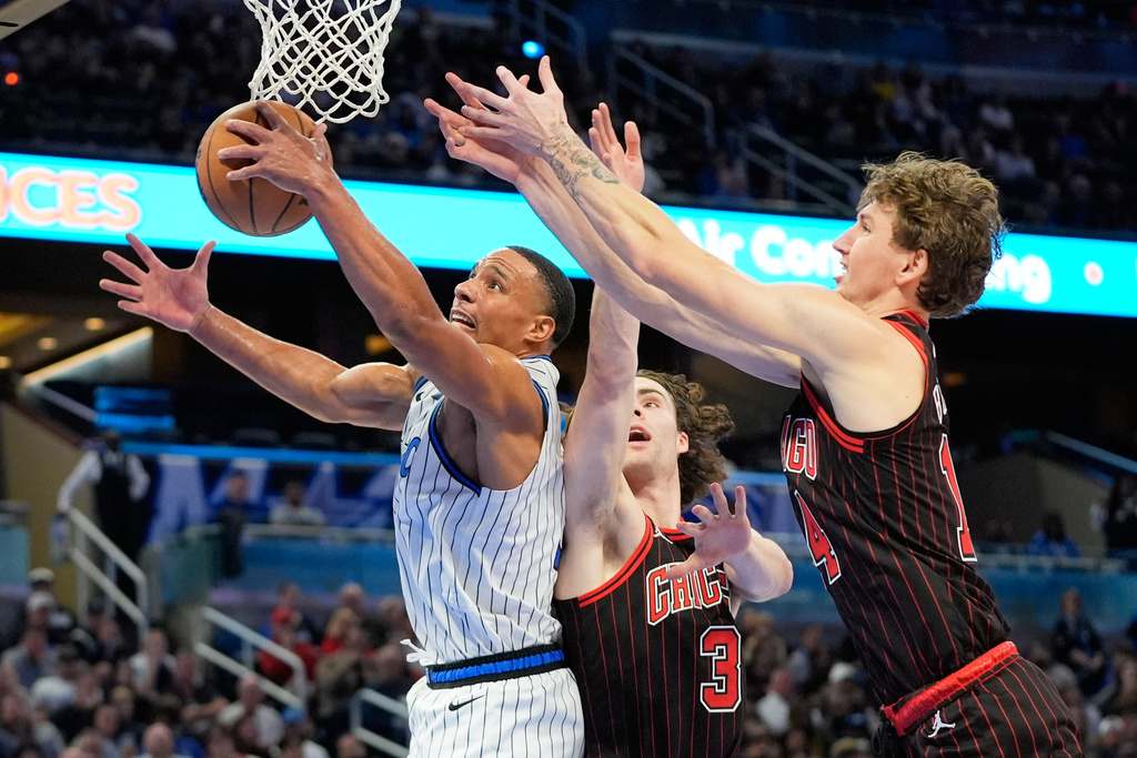 Orlando Magic guard Desmond Bane, left, grabs an offensive rebound away from Chicago Bulls guard Josh Giddey (3) and forward Matas Buzelis, right, during the first half of an NBA basketball game, Monday, Dec. 1, 2025, in Orlando, Fla. (AP Photo/John Raoux)