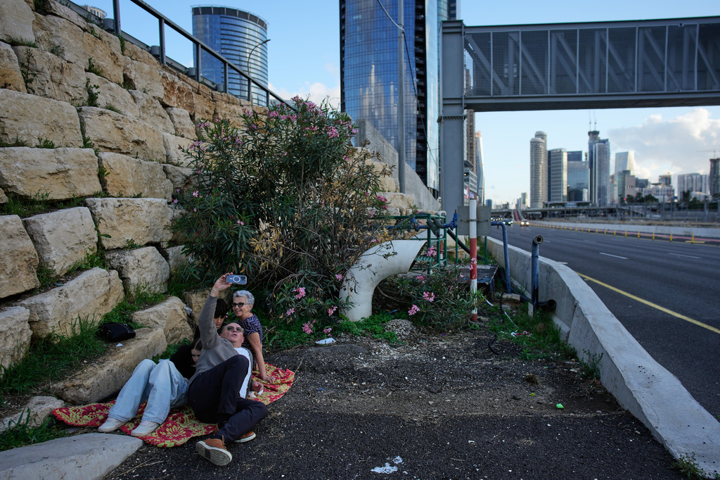 A man takes a selfie while taking cover with three others along a highway as air raid sirens warn of an incoming Iranian missile strike in Tel Aviv, Israel, Tuesday, April 7, 2026. (AP Photo/Ohad Zwigenberg)