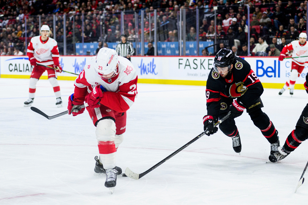 Ottawa Senators' Drake Batherson (19) fights for control of the puck caught between the skates of Detroit Red Wings' Lucas Raymond (23) during the first period of an NHL hockey game in Ottawa, Ontario, Monday, Jan. 5, 2026. (Spencer Colby/The Canadian Press via AP)