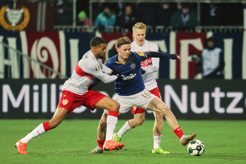 Holstein Kiel's Jonas Therkelsen, center, battles for the ball with VfB Stuttgart's Josha Vagnoman, left, and Chris Führich during a German Cup soccer match, Wednesday, Feb. 4, 2026 in Kiel, Germany. (Christian Charisius/dpa via AP)