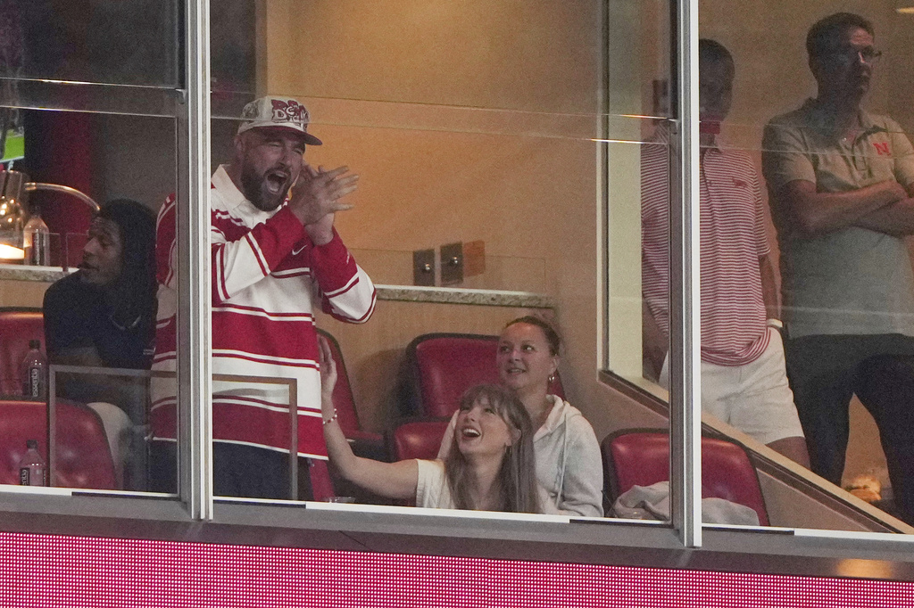 Taylor Swift sits with fiance Travis Kelce as they watch during the second half of an NCAA college football game between Cincinnati and Nebraska Thursday, Aug. 28, 2025, at Arrowhead Stadium in Kansas City, Mo. (AP Photo/Charlie Riedel)