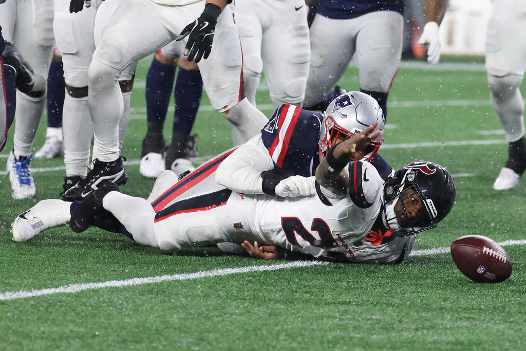 Houston Texans running back Woody Marks, bottom, looks toward the ball after fumbling, which was recovered by the New England Patriots, during the second half of an NFL divisional playoff football game, Sunday, Jan. 18, 2026, in Foxborough, Mass. (AP Photo/Mark Stockwell)