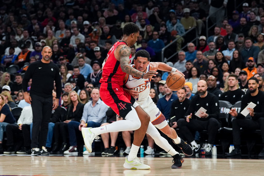 Phoenix Suns guard Devin Booker (1) collides with Houston Rockets forward Jabari Smith Jr. (10) during the first half of an NBA basketball game, Monday, Nov. 24, 2025, in Phoenix. (AP Photo/Samantha Chow)