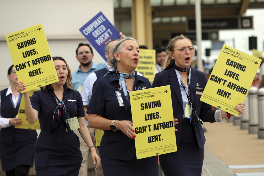 PSA Airlines flight attendants hold placards during a demonstration at Ronald Reagan Washington National Airport, Monday, August 18, 2025, in Washington. (AP Photo/Rahmat Gul)
