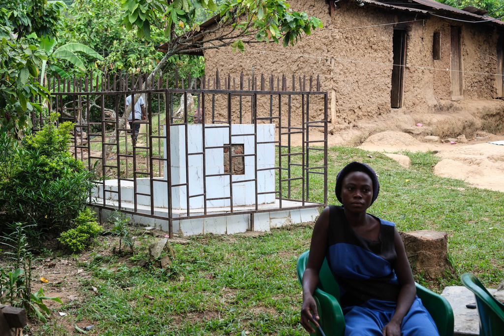 A woman sits beside a caged grave of a person who died from the first outbreak of Bundibugyo virus, a particular strain of Ebola, in Kikyo Trading village, Bundibugyo District, Uganda, Wednesday, June 3, 2026. (AP Photo/Hajarah Nalwadda)