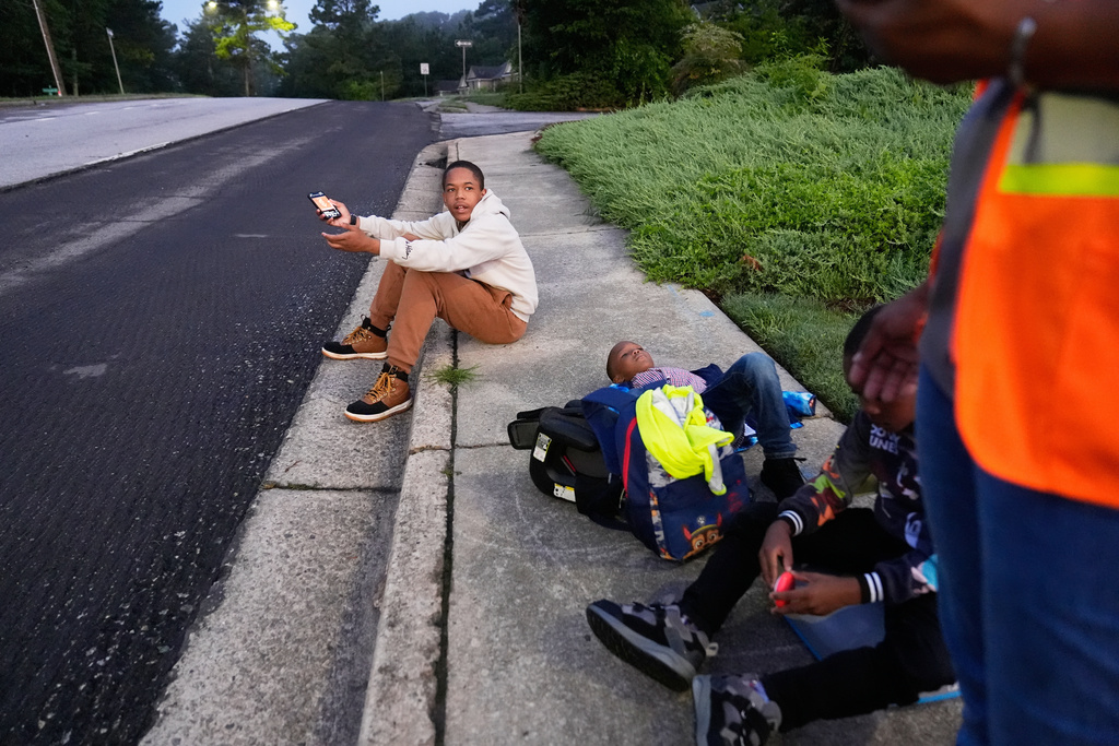 Elias Washington argues with his mother, Sechita McNair, on a sidewalk in Jonesboro, Ga., as they wait for a bus to Atlanta so Elias can attend summer school at Midtown High School, June 11, 2025. (AP Photo/Brynn Anderson)
