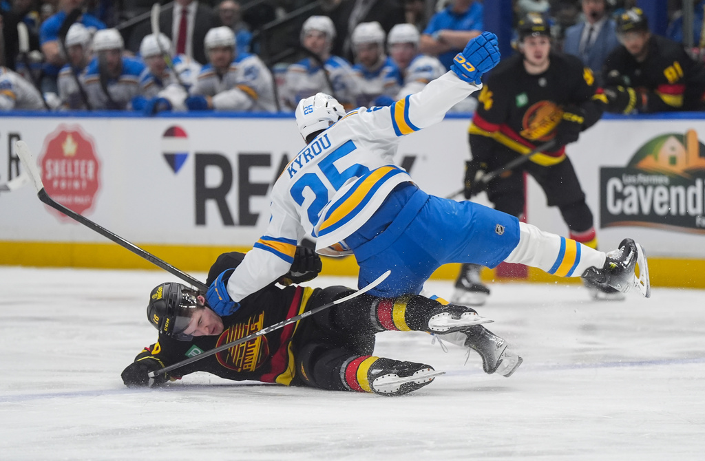 Vancouver Canucks' Drew O'Connor (18) and St. Louis Blues' Jordan Kyrou (25) collide during the first period of an NHL hockey game in Vancouver, Saturday, March 21, 2026. (Darryl Dyck/The Canadian Press via AP)