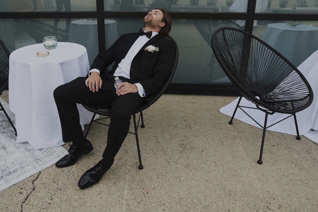 Groomsman Ethan Morton takes a break after finishing bridal party photos at a wedding on Saturday, Aug. 23, 2025, in Newtown, Ohio. (AP Photo/Joshua A. Bickel)