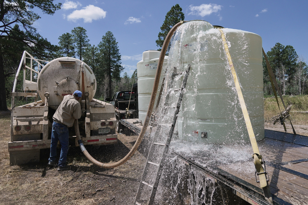 A tank overflows as Scott Snyder transfers water for his cattle, July 16, 2026 near Montrose, Colo. (AP Photo/Brittany Peterson)