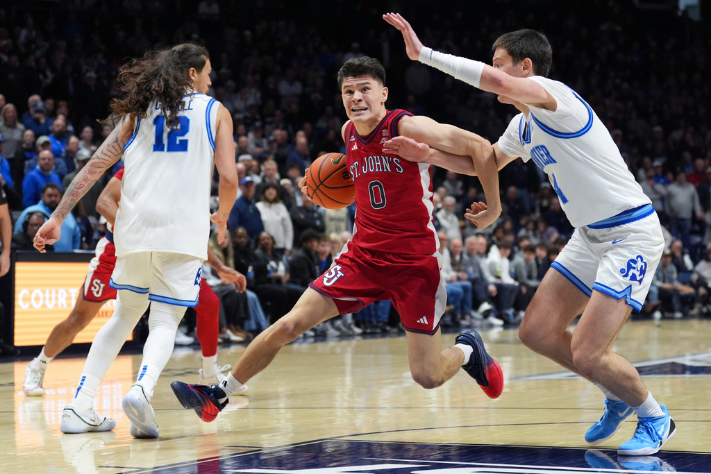 St. John's Dylan Darling, center, drives to the basket as Xavier's Filip Borovicanin, right, defends during the second half of an NCAA college basketball game, Saturday, Jan. 24, 2026, in Cincinnati. (AP Photo/Kareem Elgazzar)