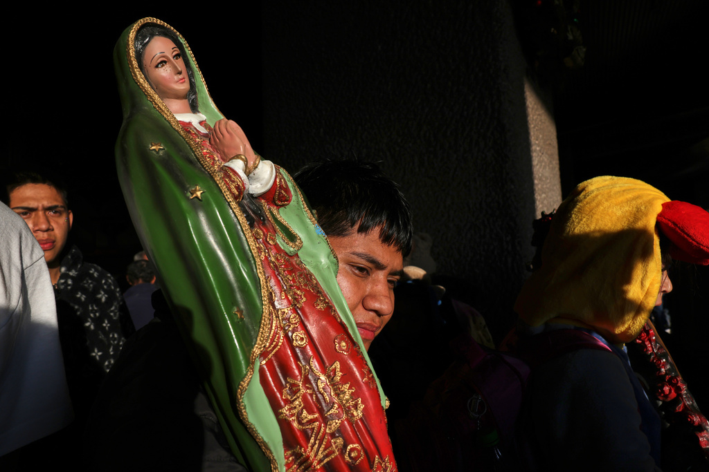 A pilgrim carrying a statue of the Virgin of Guadalupe exits the Basilica of Our Lady of Guadalupe after a Mass in Mexico City, on her feast day, Friday, Dec. 12, 2025. (AP Photo/Claudia Rosel)
