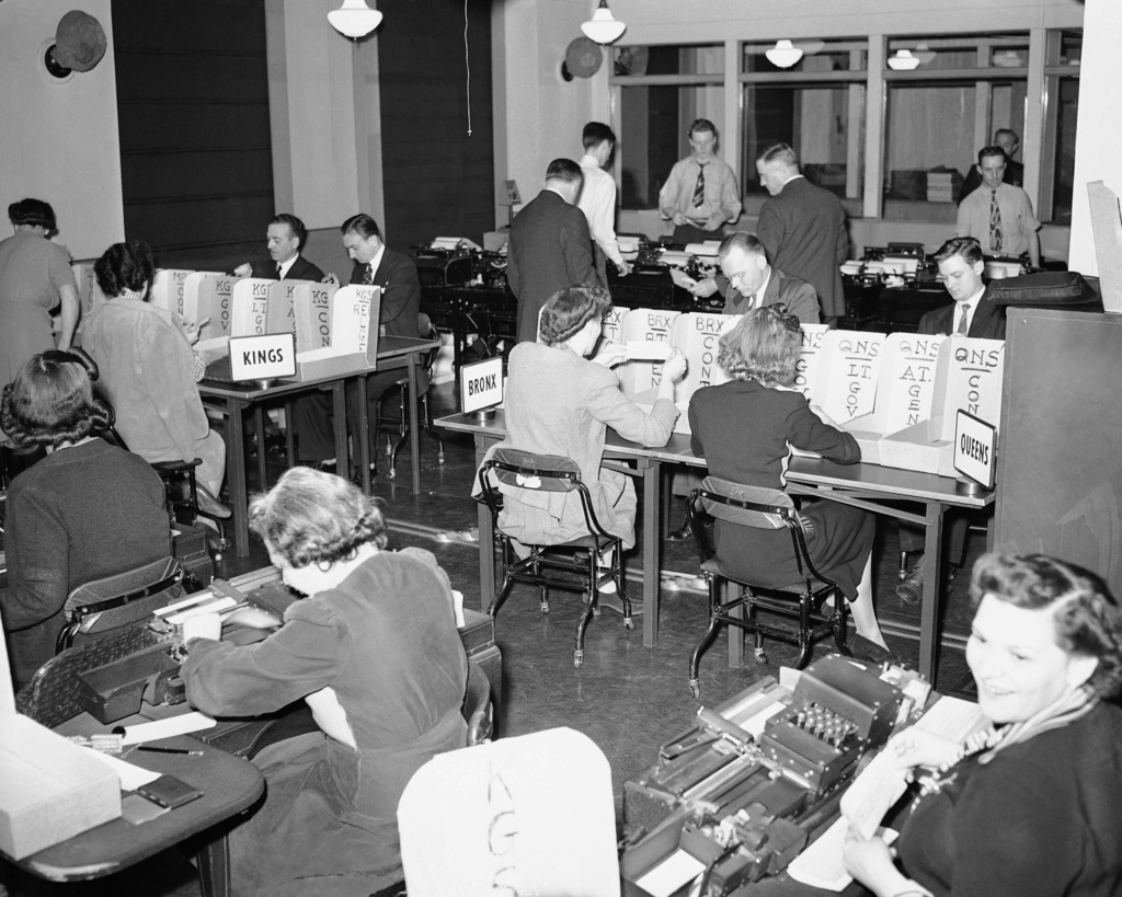 FILE - Tabulators record the Associated Press election returns in the offices of IBM in New York City on Election Day, Nov. 3, 1942. The returns are received on the teletype machines (background) and recorded with the aid of the numeric punching and printing machines in the foreground. (AP Photo/Matty Zimmerman, File)