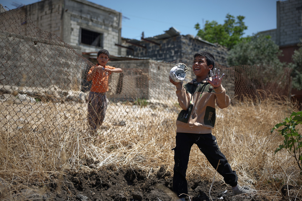 A local boy plays with the remains of an exploded Israeli shell as another boy looks on in the village of Abdin, Daraa province, Syria, Monday, June 29, 2026. (AP Photo/Ghaith Alsayed)