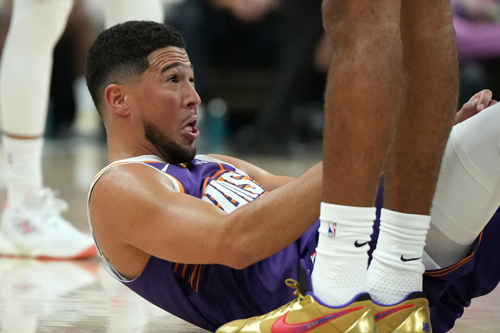 Phoenix Suns guard Devin Booker reacts after getting hit in the face during the first half of an NBA basketball game against the Sacramento Kings, Wednesday, Oct. 22, 2025, in Phoenix. (AP Photo/Rick Scuteri)
