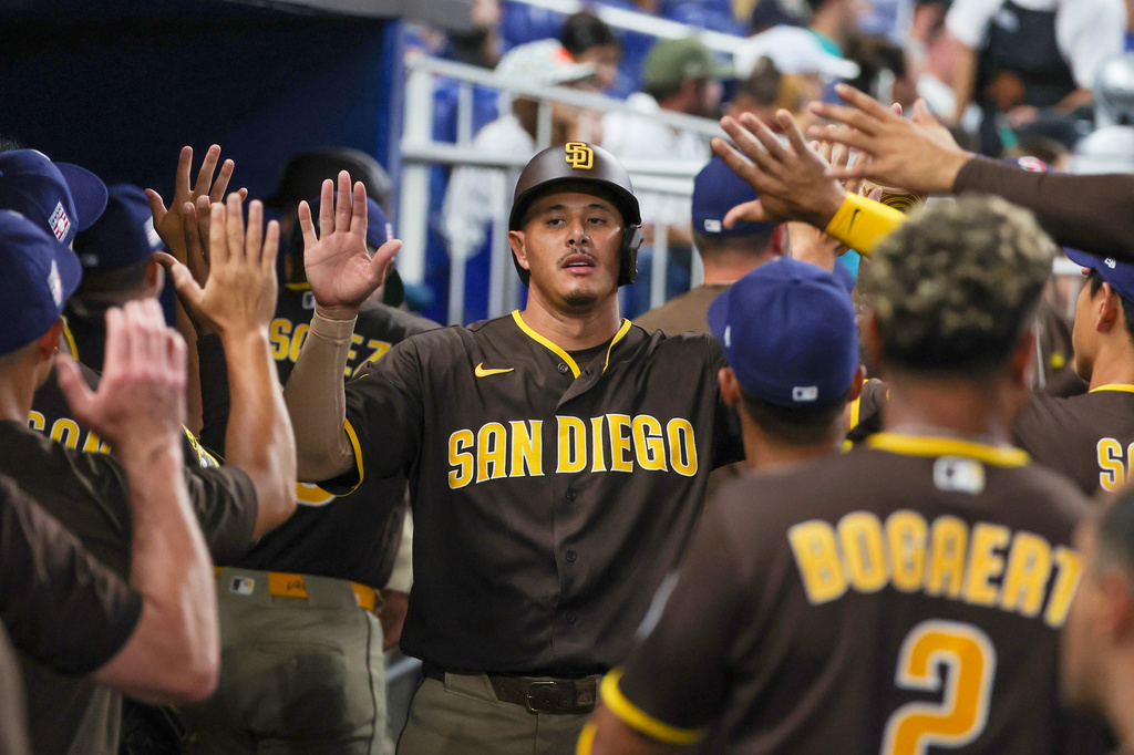 San Diego Padres' Manny Machado, center, is congratulated by teammates after scoring on a two-run single by Ty France against the Miami Marlins during the third inning of a baseball game, Saturday, July 25, 2026, in Miami. (AP Photo/David Santiago)