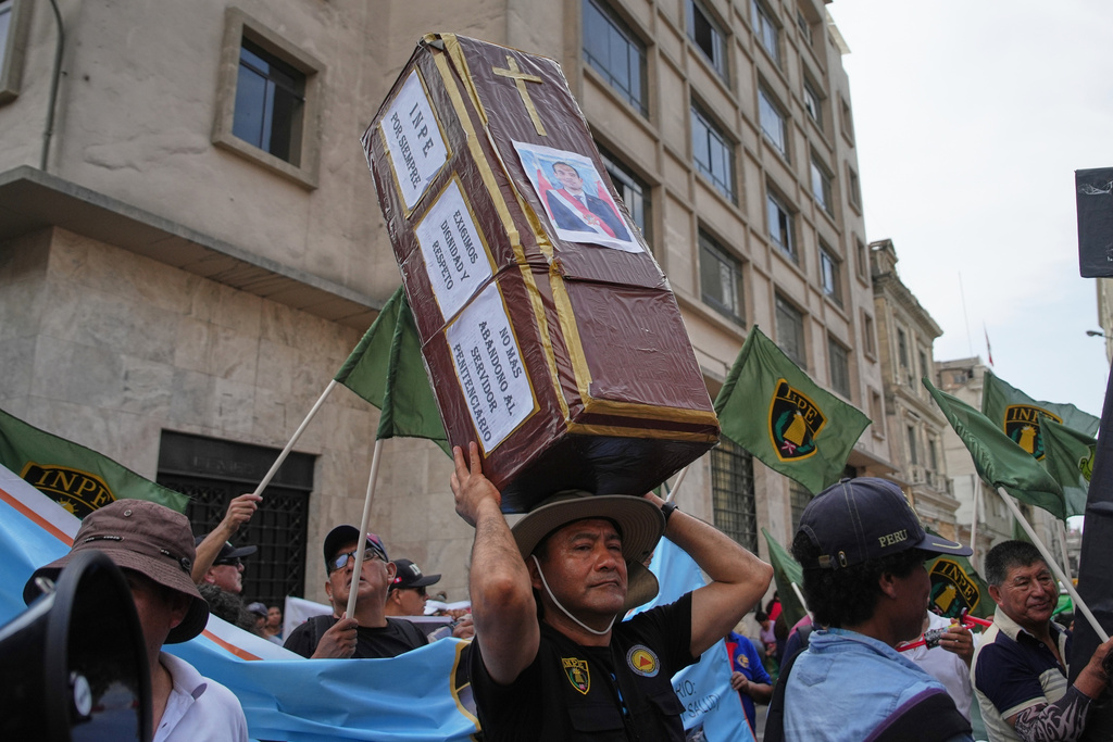 A demonstrator carries a fake coffin with a photo of interim President Jose Jeri after Congress voted to remove him, outside the site where lawmakers met in Lima, Peru, Tuesday, Feb. 17, 2026. (AP Photo/Guadalupe Pardo)