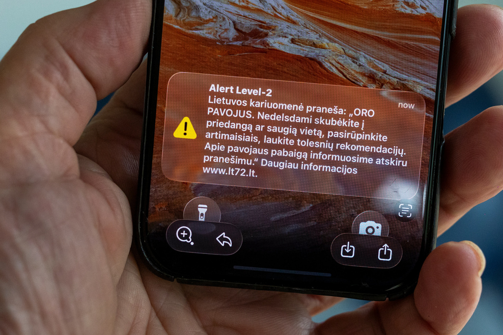 The phone shows the received message "The Lithuanian military reports: "AIR DANGER. Hurry to cover or a safe place without delay, take care of your loved ones, wait for further recommendations. We will inform you about the end of the danger in a separate message", in Vilnius, Lithuania, Wednesday, May 20, 2026. (AP Photo/Mindaugas Kulbis)