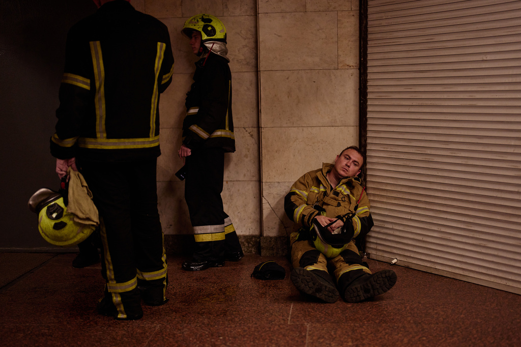 Firefighters shelter in a metro station following a siren alarm while they were trying to put out a fire at a city book market following a Russian missile attack in Kyiv, Ukraine early Sunday, Aug. 16, 2026. (AP Photo/Francisco Seco)