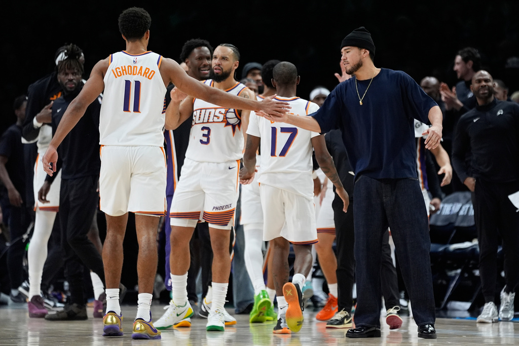 Phoenix Suns forward Oso Ighodaro (11) high-fives guard Devin Booker, right, during the second half of an NBA basketball game against the Minnesota Timberwolves, Monday, Dec. 8, 2025, in Minneapolis. (AP Photo/Abbie Parr)