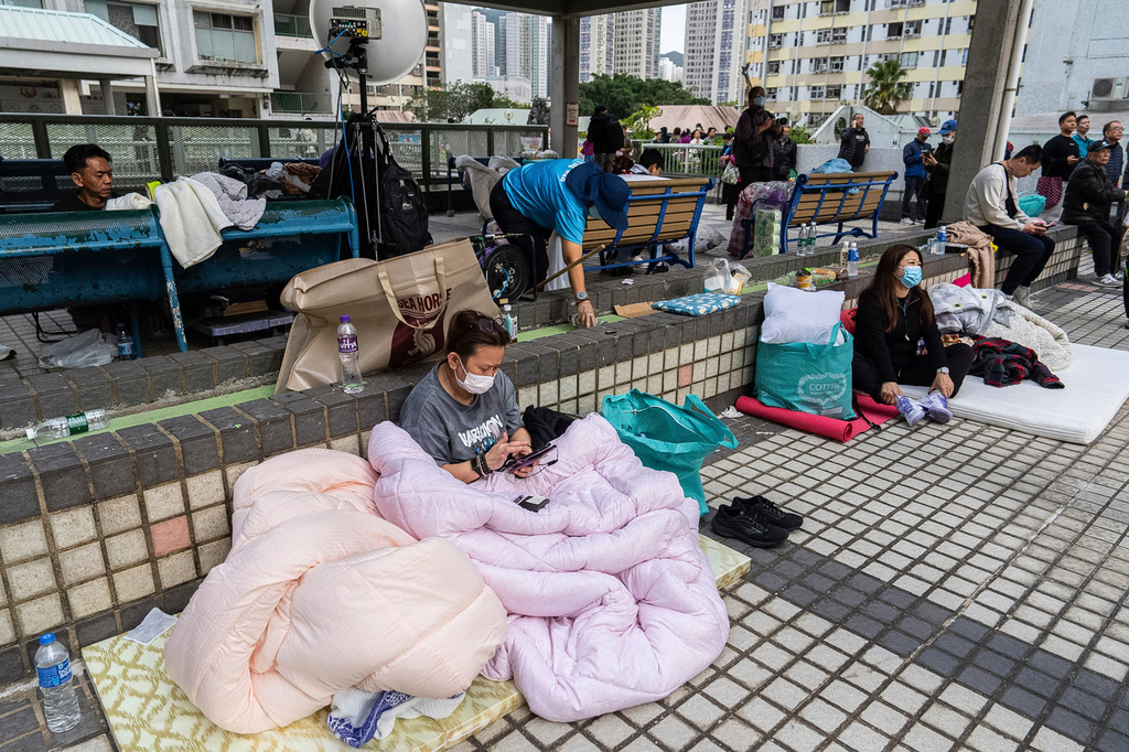 Residents rest nearby in the aftermath of a fire which broke out Wednesday at Wang Fuk Court, a residential estate in the Tai Po district of Hong Kong's New Territories, Thursday, Nov. 27, 2025. (AP Photo/Chan Long Hei)