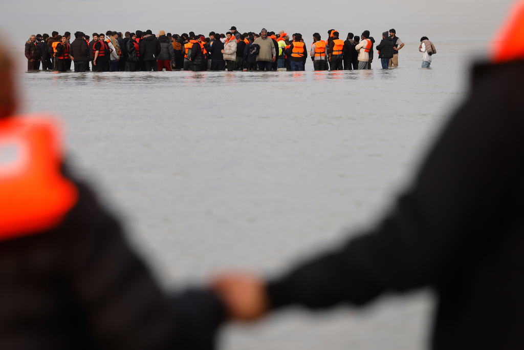 Migrants push a small boat in an attempt to reach Britain, Thursday, Nov. 6, 2025 in Gravelines, northern France. (AP Photo/Jean-Francois Badias)
