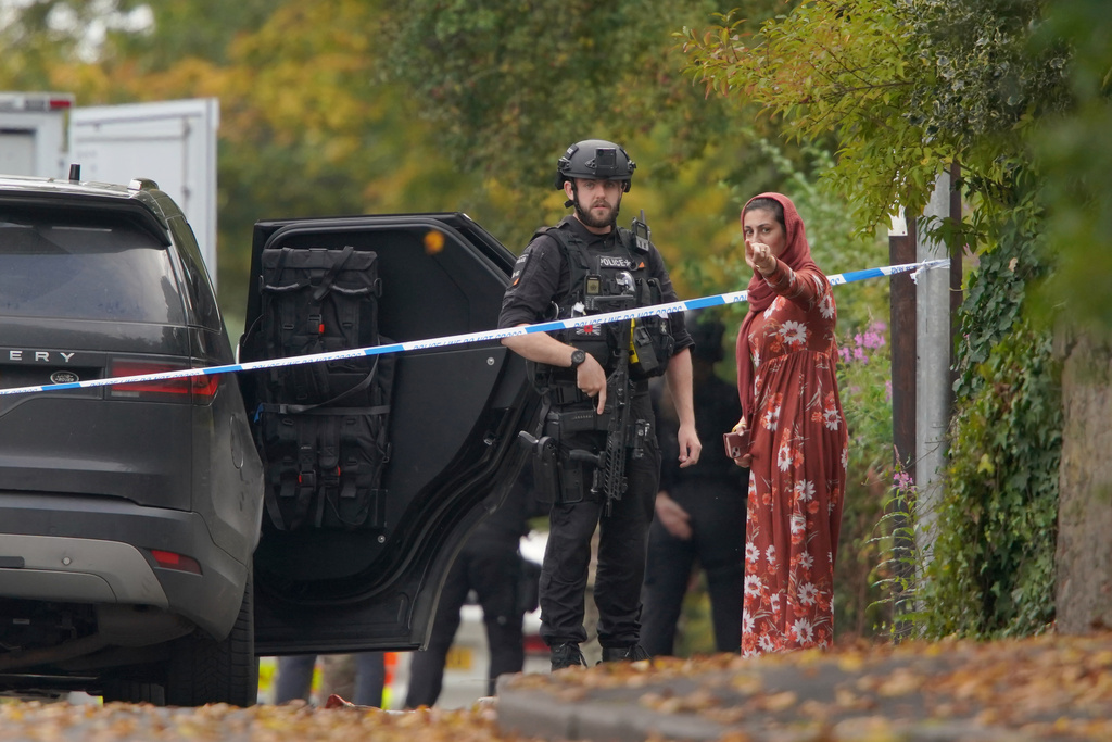 An armed police officer speaks to member of the public near the scene of a stabbing incident at Heaton Park Hebrew Congregation synagogue, in Crumpsall, Manchester, England, Thursday, Oct. 2, 2025. (AP Photo/Ian Hodgson)