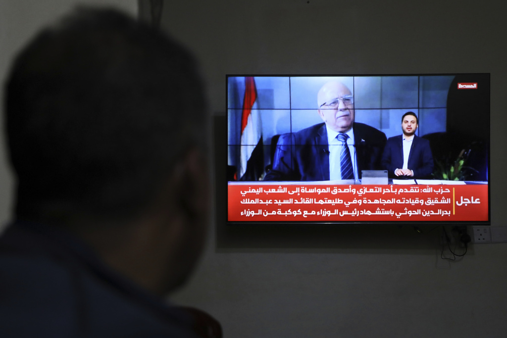 A man watches the news on TV, displaying footage of Ahmed al-Rahawi, the prime minister of the Houthi-controlled government, who was killed, along with others, in Thursday's Israeli strikes on the capital, in Sanaa, Yemen, Saturday, Aug. 30, 2025. (AP Photo/Osamah Abdulrahman)
