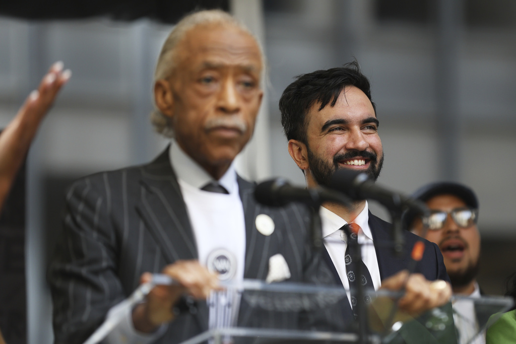 New York City Democratic mayoral candidate Zohran Mamdani smiles behind Rev. Al Sharpton on stage for the March on Wall Street, Thursday, Aug. 28, 2025, in New York. (AP Photo/Heather Khalifa)