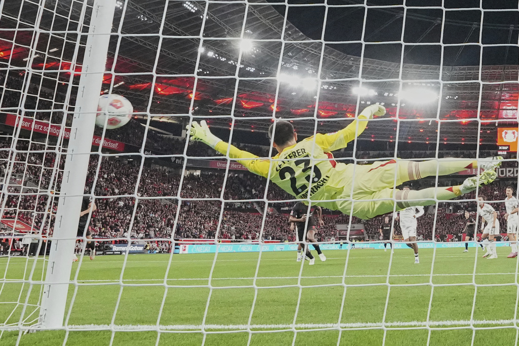Frankfurt's goalkeeper Michael Zetterer receives the opening goal by Leverkusen's Alex Grimaldo during the German Bundesliga soccer match between Bayer Leverkusen and Eintracht Frankfurt at the BayArena in Leverkusen, Germany, Friday, Sept. 12, 2025. (AP Photo/Martin Meissner)