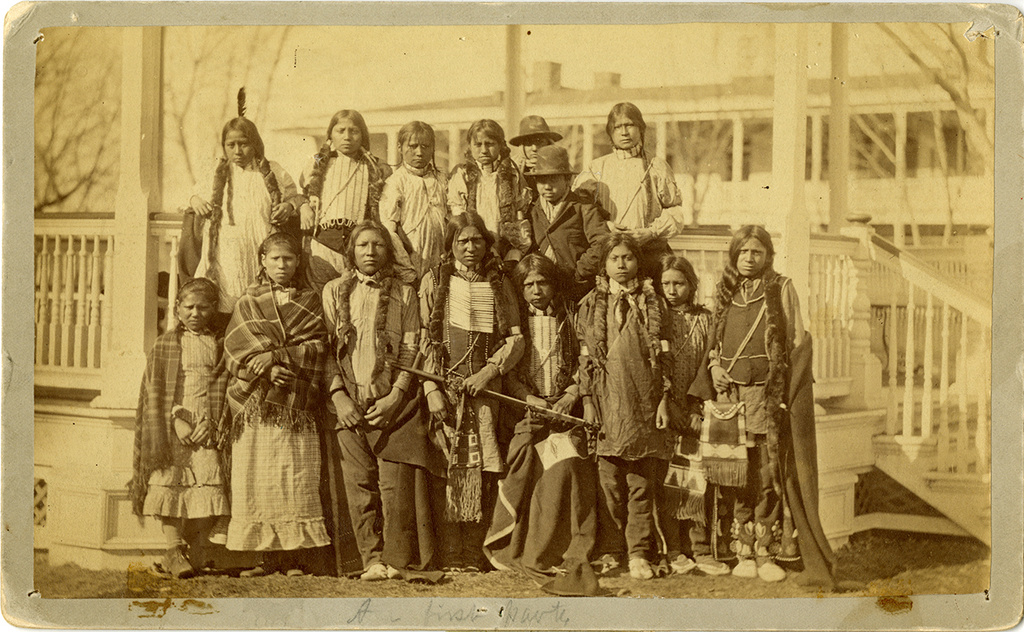 This photo provided by the Carlisle Indian School Digital Resource Center shows nine male students and six female students posed on the steps of the bandstand on the Carlisle Indian Industrial School grounds in Carlisle, Pa., in March 1891, wearing the clothing they arrived in. (John N. Choate/Carlisle Indian School Digital Resource Center via AP)