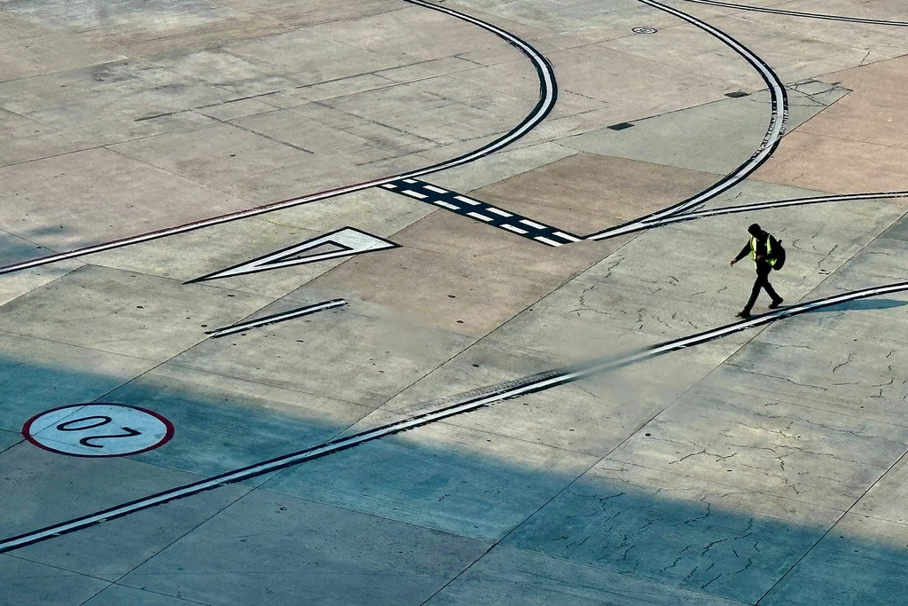 An airport official walks near a runway at the Indira Gandhi International Airport in New Delhi as several Indigo Airlines flights were cancelled or delayed, India, Thursday, Dec. 4, 2025. (AP Photo/Manish Swarup)