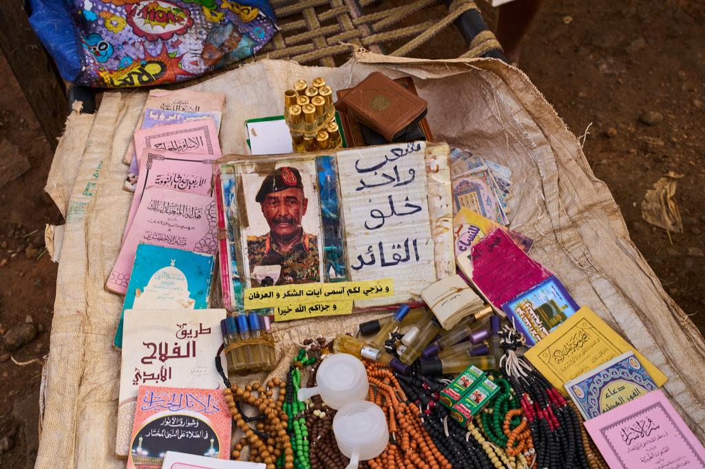 A picture of Sudan's army chief Gen. Abdel-Fattah Burhan, next to writing in Arabic that reads, "One people created the leader," sits among religious items for sale at a market in Omdurman, on the outskirts of Khartoum, Sudan, Sunday, April 26, 2026. (AP Photo/Bernat Armangue)