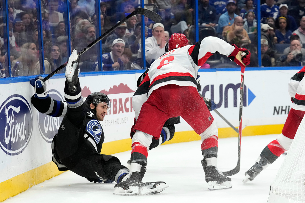Tampa Bay Lightning center Dominic James (17) gets knocked down by Carolina Hurricanes defenseman Mike Reilly (6) during the second period of an NHL hockey game Saturday, Dec. 20, 2025, in Tampa, Fla. (AP Photo/Chris O'Meara)