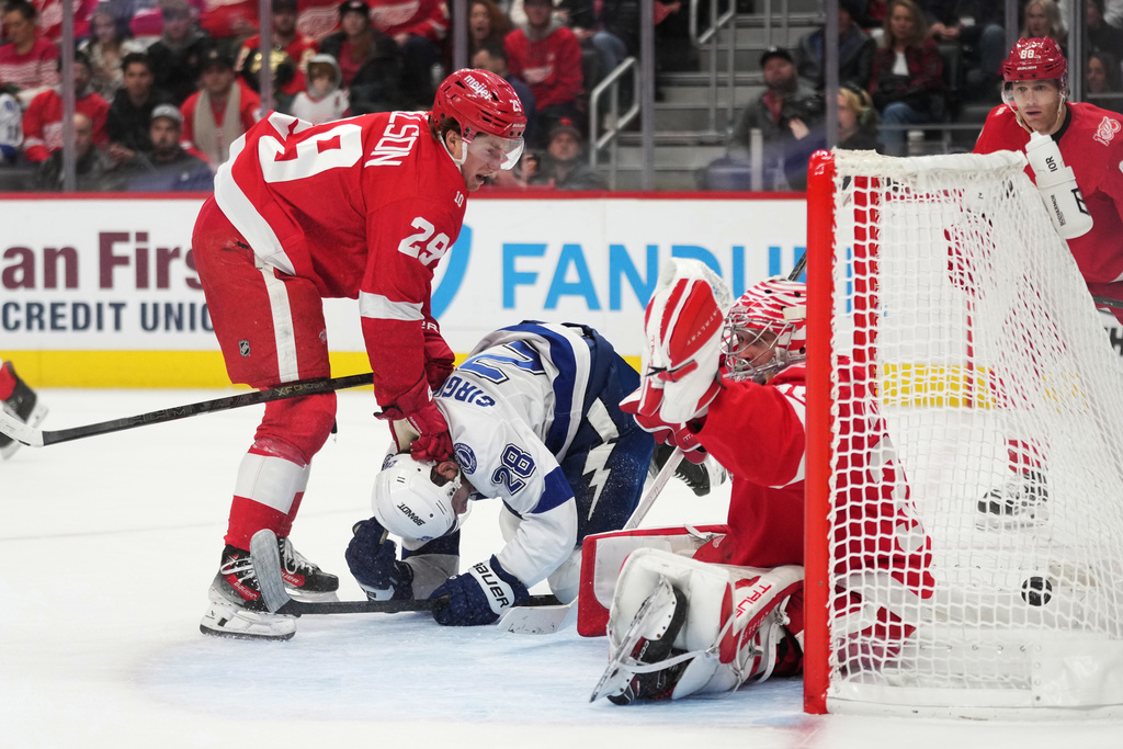 Detroit Red Wings goaltender John Gibson, right, is unable to block a goal scored by Tampa Bay Lightning center Yanni Gourde, not pictured, as center Nate Danielson, left, defends center Zemgus Girgensons, center, during the second period of an NHL hockey game Friday, Nov. 28, 2025, in Detroit. (AP Photo/Ryan Sun)