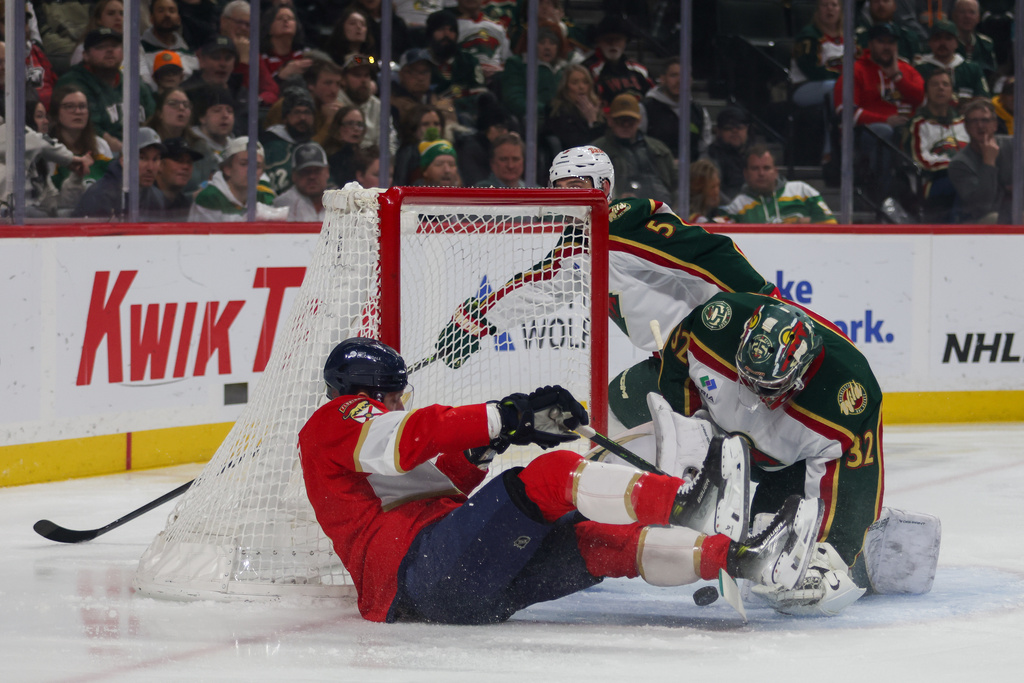 Florida Panthers' Sam Bennett, left, trips over Minnesota Wild goalie Filip Gustavsson (32) during the first period of an NHL hockey game, Saturday, Jan. 24, 2026, in St. Paul, Minn. (AP Photo/Lily Dozier)