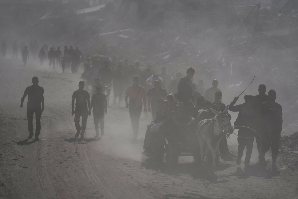 Displaced Palestinians walk past destroyed buildings as they return to their homes in the Zeitoun neighborhood of Gaza City, Friday, Oct. 10, 2025, after Israel and Hamas agreed to a pause in their war and the release of remaining hostages. (AP Photo/Jehad Alshrafi)
