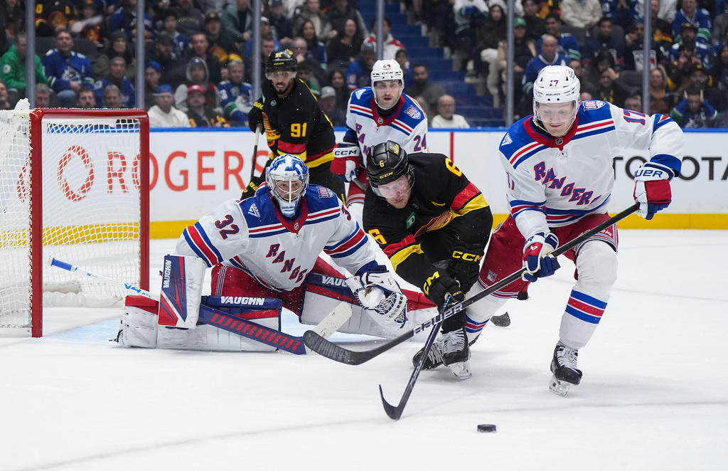 Vancouver Canucks' Brock Boeser (6) and New York Rangers' Will Borgen (17) vie for the puck after goalie Jonathan Quick (32) made the save during the third period of an NHL hockey game, in Vancouver, on Tuesday, Oct. 28, 2025. (Darryl Dyck/The Canadian Press via AP)