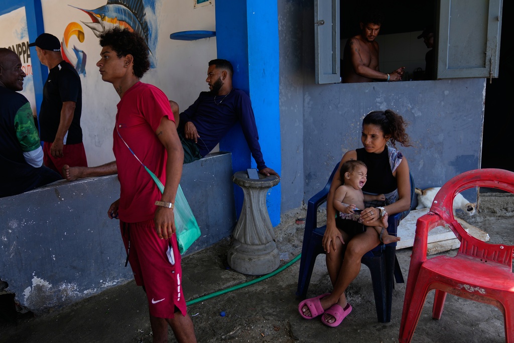 Residents and fisherman stand near Macuto beach in Venezuela, Wednesday, Dec. 17, 2025. (AP Photo/Ariana Cubillos)