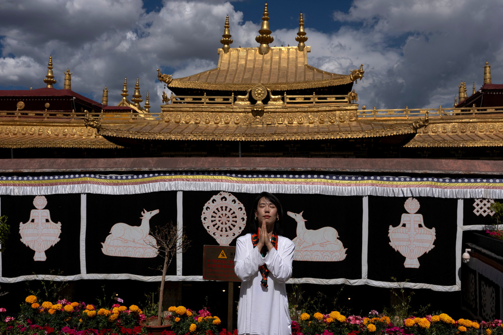 A tourist poses for a photo at Jokhang Temple in Lhasa in western China's Tibet Autonomous Region on Tuesday, July 21, 2026, as seen during a government organized visit for foreign journalists. (AP Photo/Ng Han Guan)