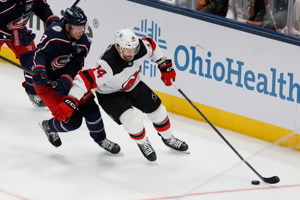 New Jersey Devils' Luke Glendening, right, keeps the puck away from Columbus Blue Jackets' Charlie Coyle, left, during the third period of an NHL hockey game, Monday, Oct. 13, 2025, in Columbus, Ohio. (AP Photo/Jay LaPrete)