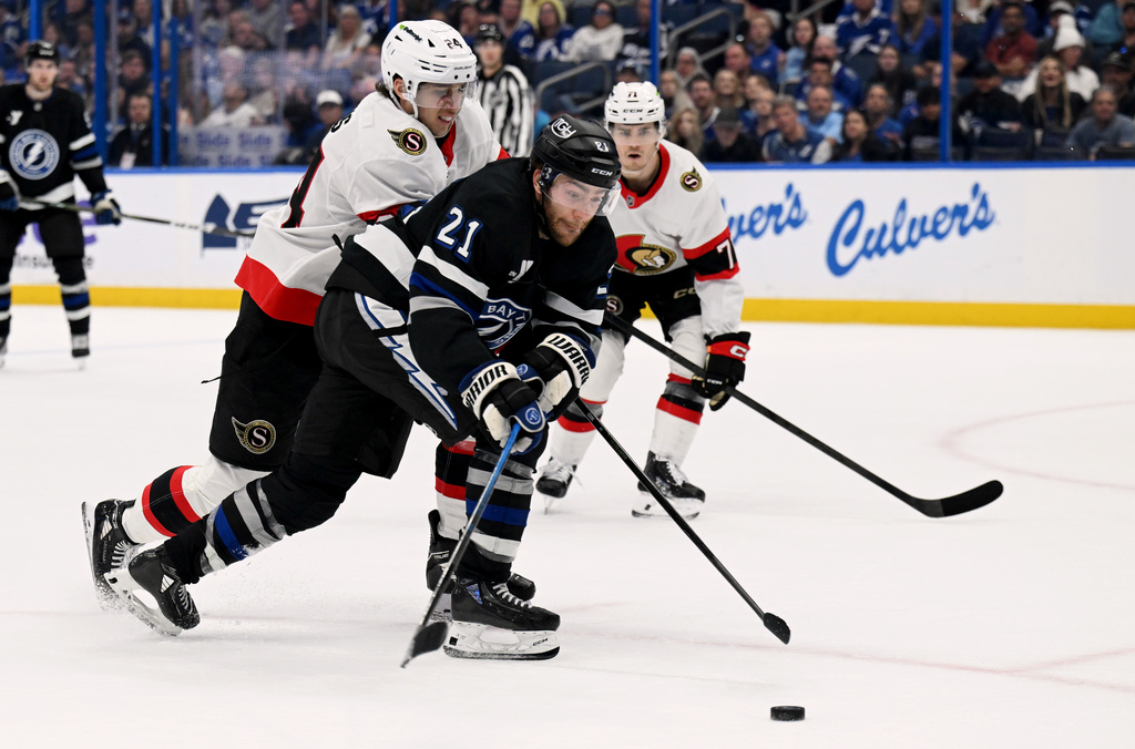 Tampa Bay Lightning center Brayden Point (21) and Ottawa Senators center Dylan Cozens (24) battle for the puck during the second period of an NHL hockey game Saturday, March 28, 2026, in Tampa, Fla. (AP Photo/Jason Behnken)