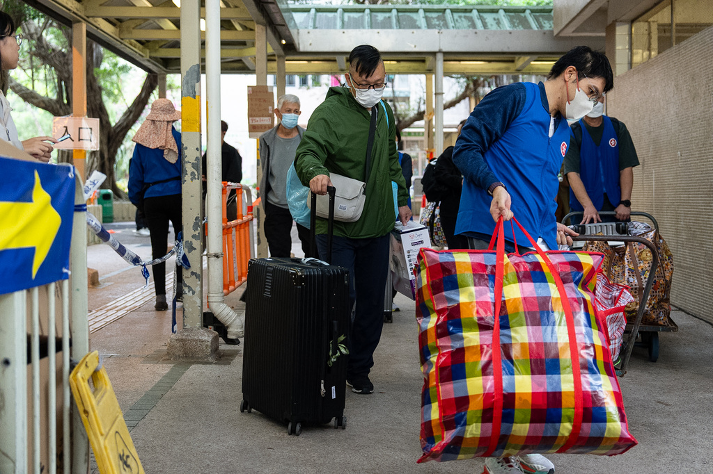 Residents are assisted by the Government Quick Response Unit as they return to their homes to collect belongings after the fire at Wang Fuk Court, a residential estate in the Tai Po district of Hong Kong's New Territories on Wednesday, Dec 3, 2025. (AP Photo/Chan Long Hei)