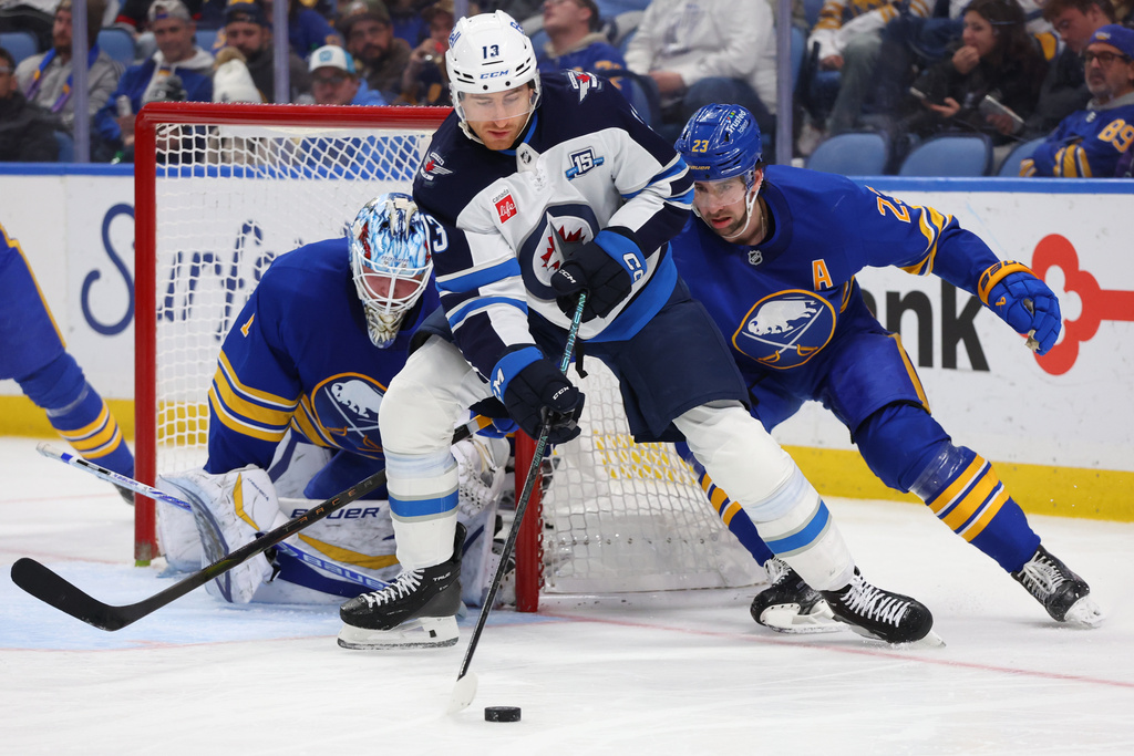 Winnipeg Jets center Gabriel Vilardi (13) carries the puck in front of Buffalo Sabres goaltender Ukko-Pekka Luukkonen, left, and defenseman Mattias Samuelsson (23) during the second period of an NHL hockey game Monday, Dec. 1, 2025, in Buffalo, N.Y. (AP Photo/Jeffrey T. Barnes)