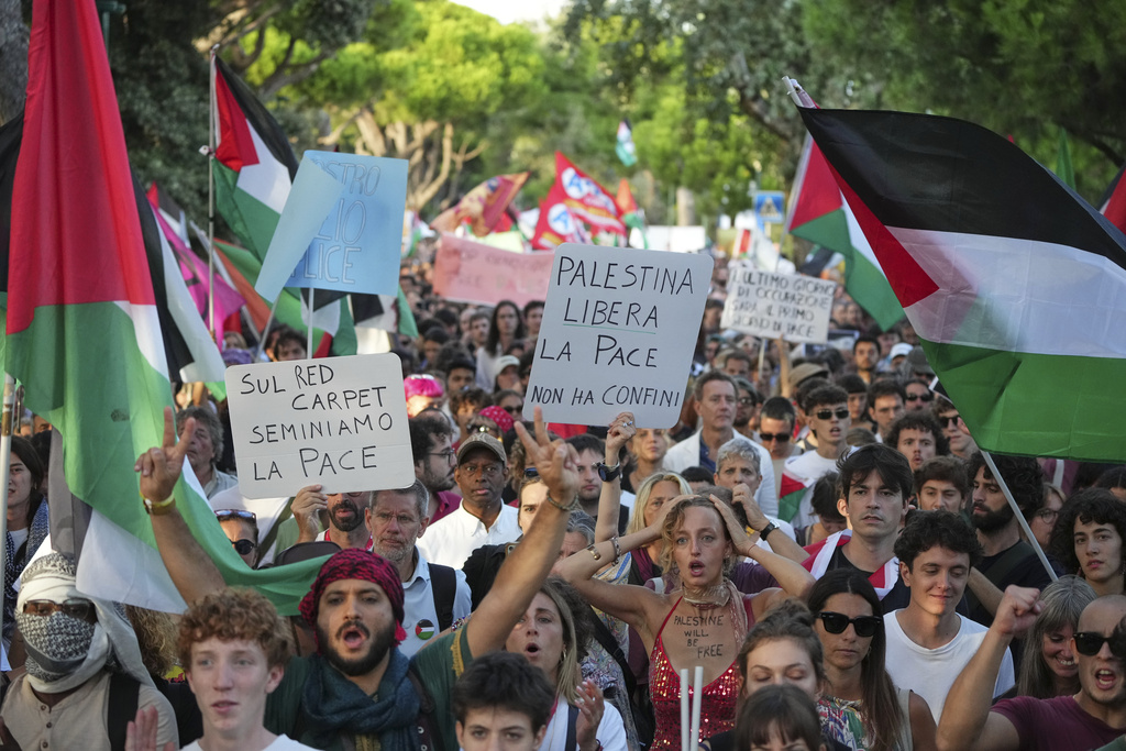 Demonstrators, from left, hold placards that read 'On the red carpet lets sow peace' and 'Free Palestine, peace has no borders' during a march in support of the Palestinian people in Gaza, during the Film Festival in Venice, Italy, Saturday, Aug. 30, 2025. (Photo by Alessandra Tarantino/Invision/AP)