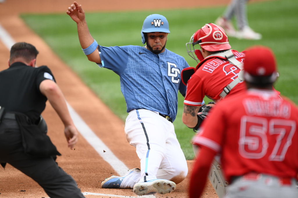 Washington Nationals' Keibert Ruiz, center, slides home to score on a single by Jacob Young against Los Angeles Angels catcher Tyler Heineman (31) during the second inning of a baseball game, Saturday, Sept. 12, 2026, in Washington. (AP Photo/Nick Wass)