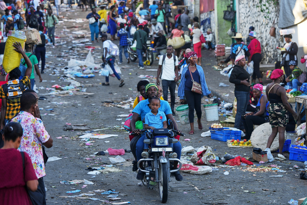 A moto-taxi driver transports clients through the Petion-Ville area of of Port-au-Prince, Haiti, Monday, March 16, 2026. (AP Photo/Odelyn Joseph)